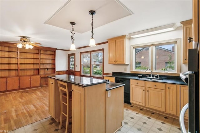 kitchen featuring a sink, black dishwasher, a center island, light floors, and dark countertops