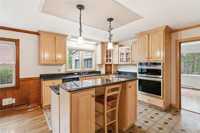 kitchen with baseboard heating, double oven, wainscoting, light brown cabinets, and a sink