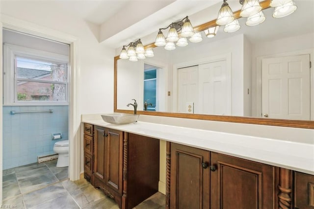 bathroom featuring toilet, tile walls, and vanity