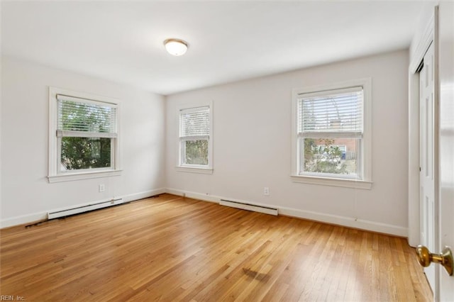 unfurnished bedroom featuring a baseboard heating unit, baseboards, and light wood finished floors