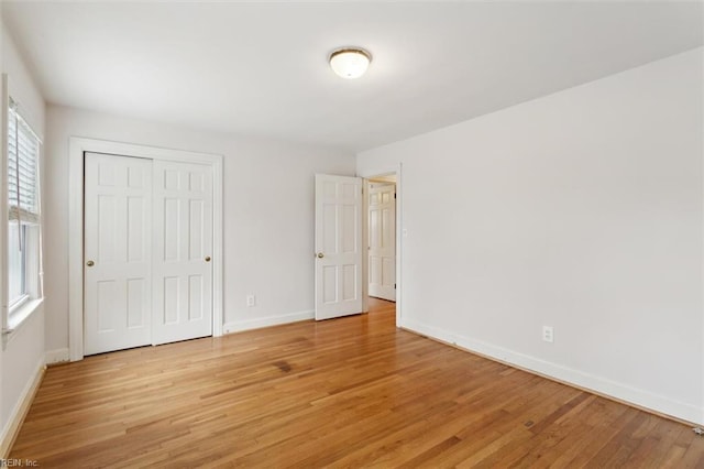 unfurnished bedroom featuring a closet, light wood-style flooring, and baseboards