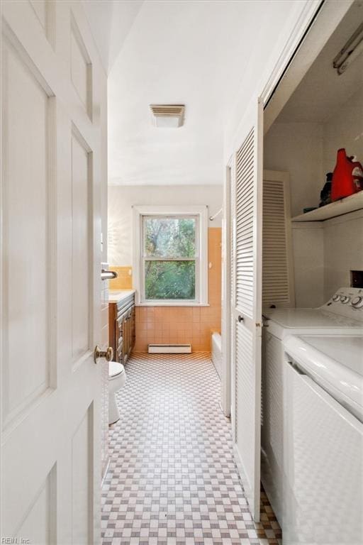 interior space with visible vents, washer and clothes dryer, tile patterned floors, vanity, and a baseboard heating unit