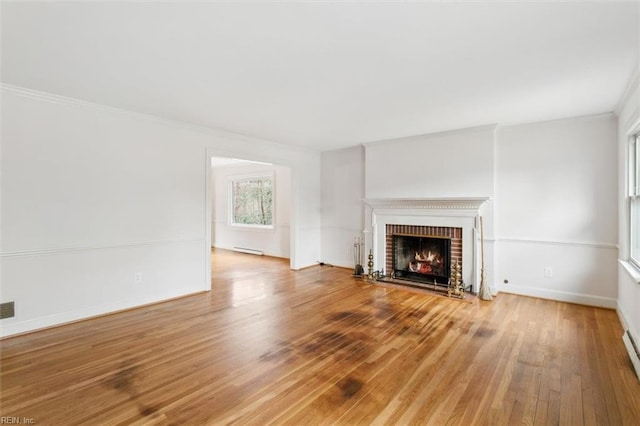 unfurnished living room featuring a baseboard radiator, ornamental molding, a brick fireplace, wood finished floors, and baseboards