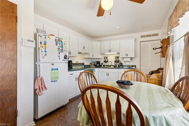 kitchen with under cabinet range hood, white cabinetry, electric stove, freestanding refrigerator, and dark countertops