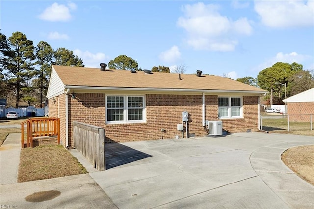 rear view of property featuring brick siding and central AC