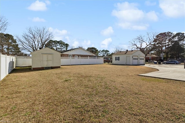 view of yard featuring a garage, a fenced backyard, a shed, and an outbuilding