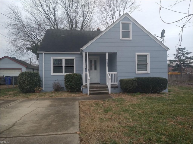 bungalow-style house with covered porch, roof with shingles, and a front lawn