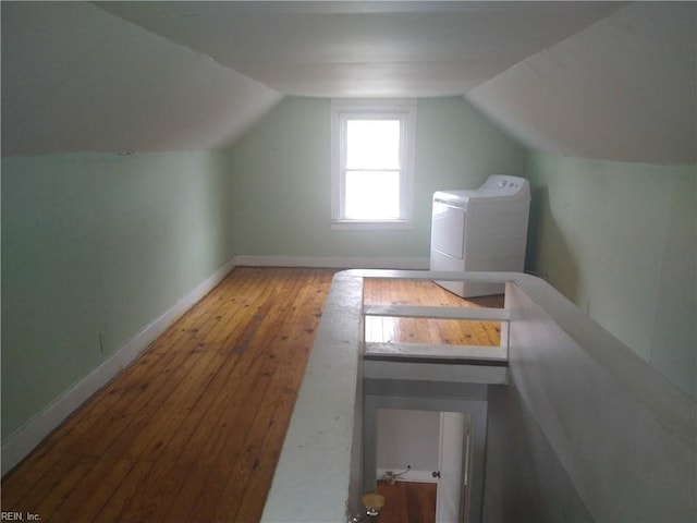 additional living space featuring lofted ceiling, washer / clothes dryer, hardwood / wood-style flooring, and baseboards