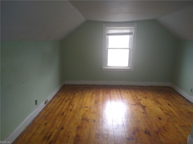 additional living space with vaulted ceiling, hardwood / wood-style floors, and baseboards