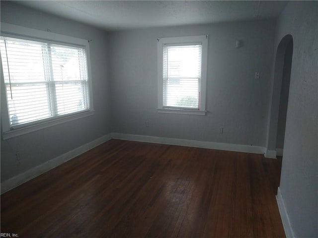 unfurnished room with dark wood-style floors, plenty of natural light, and baseboards