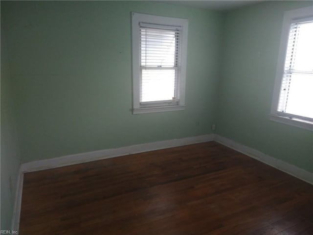 empty room with dark wood finished floors and baseboards