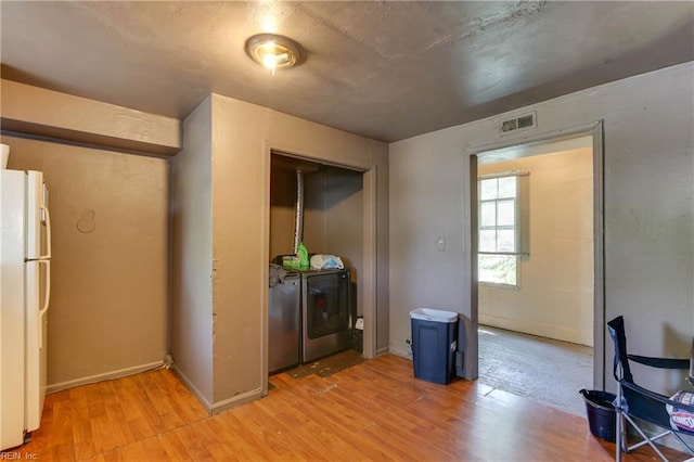 kitchen with light wood-style floors, freestanding refrigerator, visible vents, and separate washer and dryer