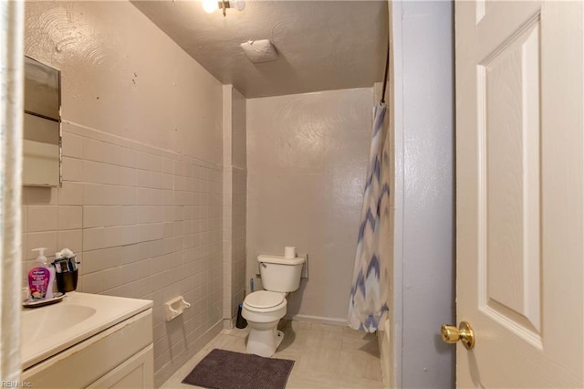 full bathroom featuring a shower with shower curtain, toilet, tile patterned flooring, vanity, and tile walls