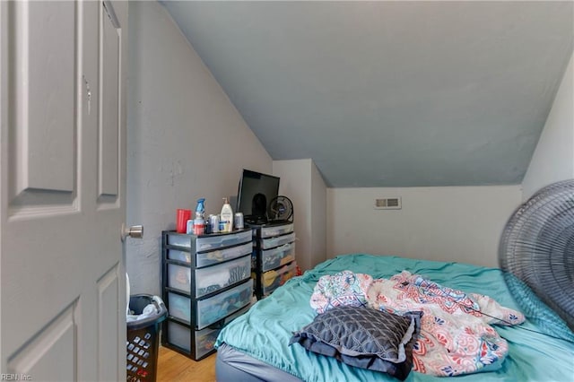 bedroom featuring light wood-style floors, visible vents, and vaulted ceiling