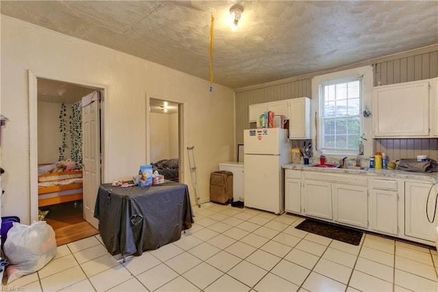 kitchen featuring white cabinets, light countertops, a sink, and freestanding refrigerator