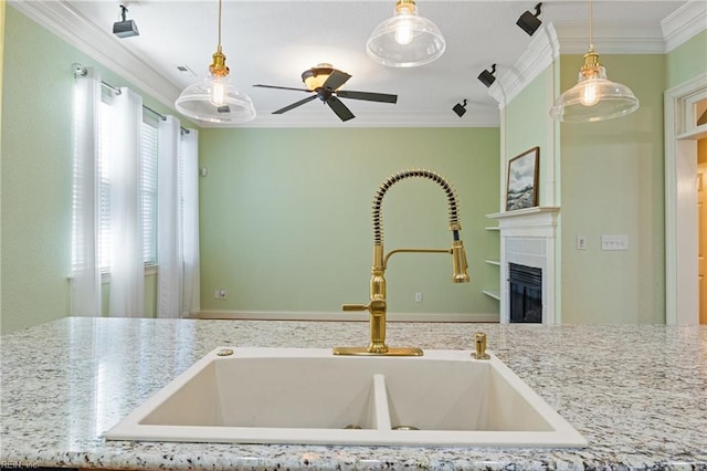 kitchen featuring hanging light fixtures, crown molding, a fireplace, and a sink