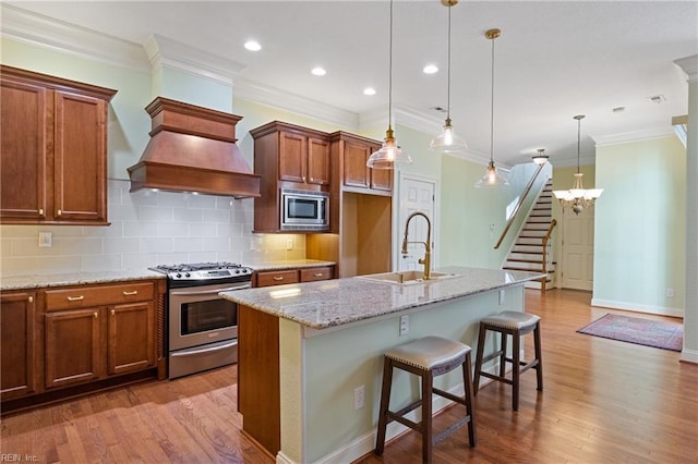 kitchen featuring stainless steel appliances, brown cabinetry, a sink, and light wood-style floors