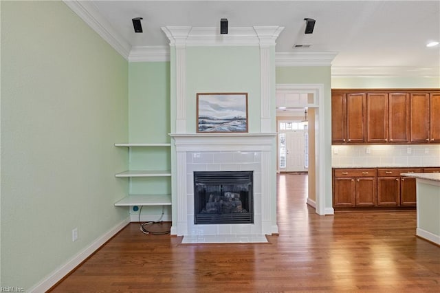 unfurnished living room featuring baseboards, a tile fireplace, wood finished floors, and crown molding