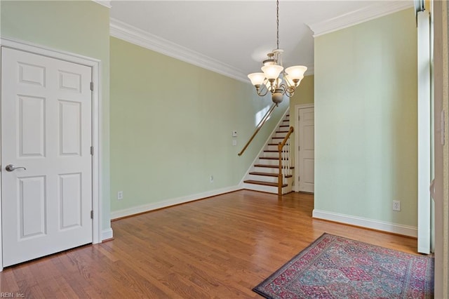 interior space featuring baseboards, wood finished floors, stairs, crown molding, and a notable chandelier