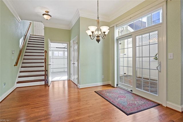 entryway with an inviting chandelier, crown molding, baseboards, and wood finished floors