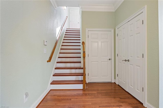 stairs with ornamental molding, baseboards, and wood finished floors