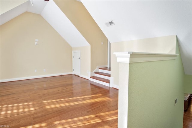 bonus room featuring visible vents, vaulted ceiling, baseboards, and wood finished floors