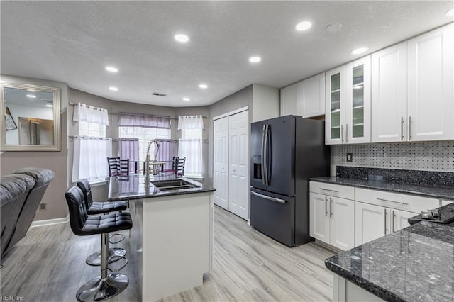 kitchen with glass insert cabinets, white cabinets, and black fridge with ice dispenser