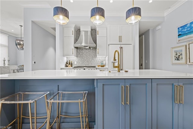 kitchen featuring light countertops, white cabinets, crown molding, wall chimney exhaust hood, and backsplash