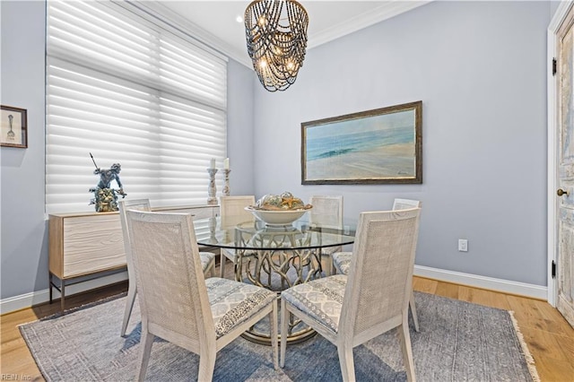 dining space with baseboards, a notable chandelier, wood finished floors, and crown molding