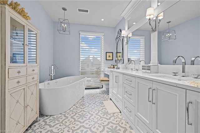 bathroom featuring a sink, visible vents, a soaking tub, and double vanity