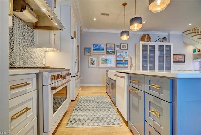 kitchen with ornamental molding, under cabinet range hood, tasteful backsplash, light countertops, and high end appliances