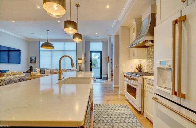 kitchen with crown molding, open floor plan, white appliances, wall chimney exhaust hood, and a sink