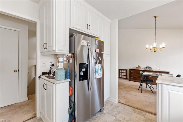 kitchen with lofted ceiling, light colored carpet, white cabinetry, light countertops, and stainless steel fridge