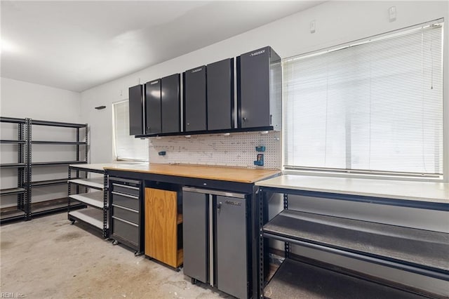 kitchen with tasteful backsplash, concrete flooring, and refrigerator