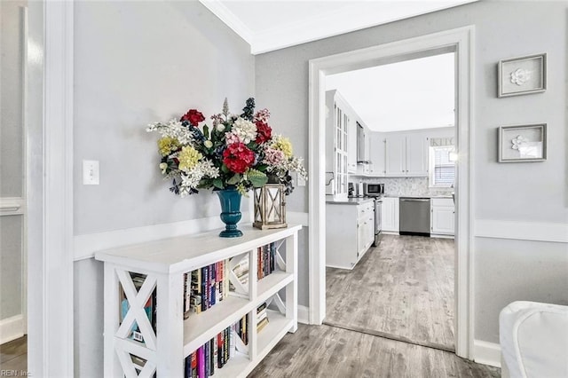 corridor featuring light wood-style floors and crown molding