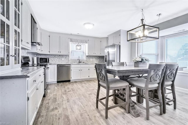 kitchen featuring light wood-style floors, appliances with stainless steel finishes, decorative backsplash, and a sink