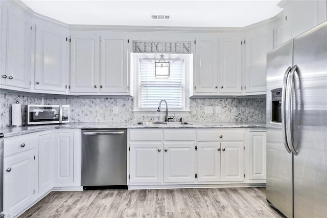 kitchen with appliances with stainless steel finishes, light wood-type flooring, a sink, and white cabinets