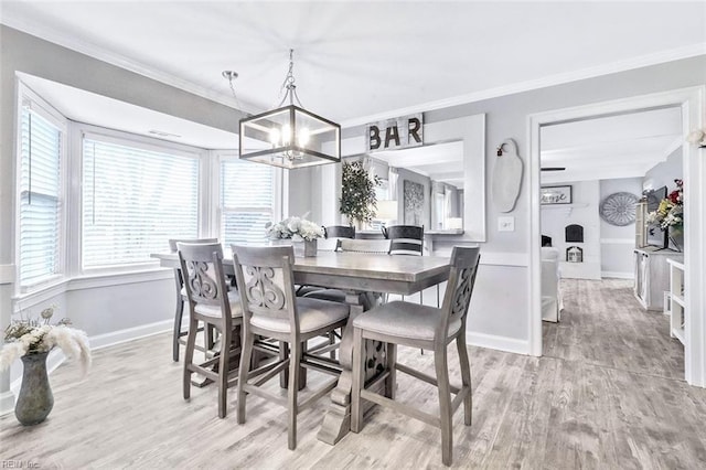 dining area featuring ornamental molding, a chandelier, baseboards, and wood finished floors