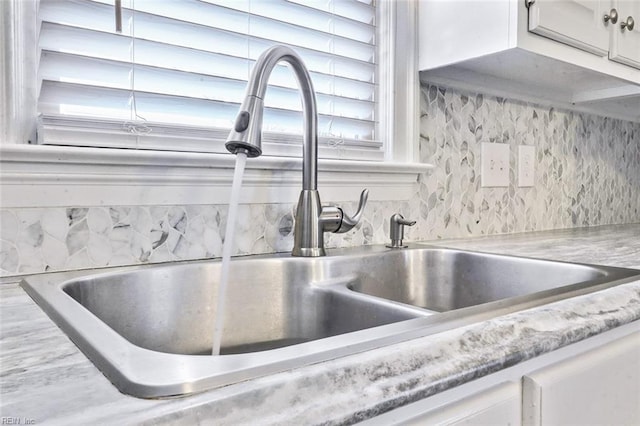 details featuring white cabinetry, a sink, and decorative backsplash