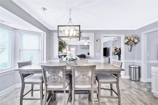 dining space with baseboards, ornamental molding, light wood-style floors, and a notable chandelier