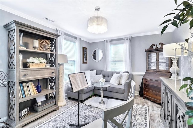 living area with ornamental molding, visible vents, light wood-style floors, and baseboards