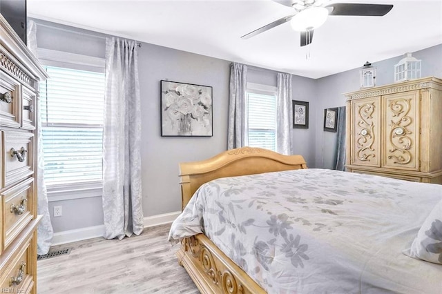 bedroom with a ceiling fan, light wood-type flooring, visible vents, and baseboards