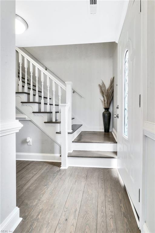 staircase with wood-type flooring, visible vents, and baseboards