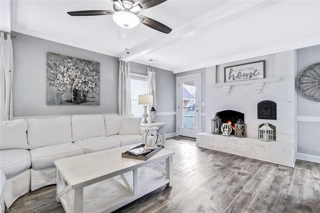 living area featuring a fireplace, crown molding, a ceiling fan, wood finished floors, and baseboards