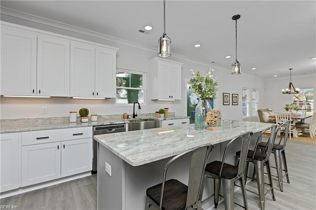 kitchen with crown molding, stainless steel dishwasher, white cabinetry, a sink, and a kitchen bar