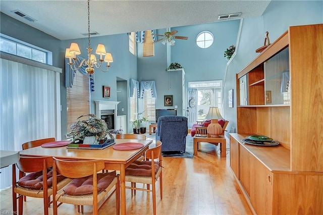 dining space with visible vents, a fireplace, light wood-style flooring, and a textured ceiling