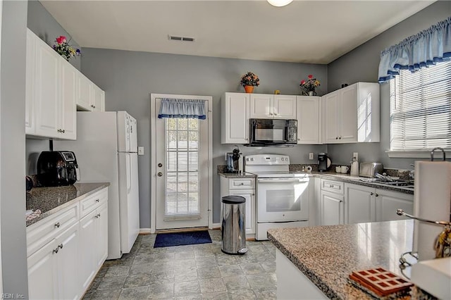 kitchen with white appliances, visible vents, a sink, and white cabinetry