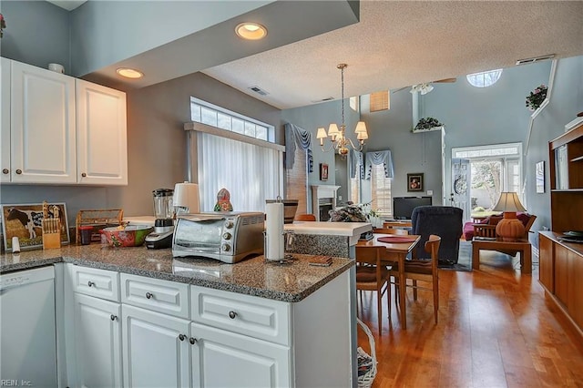 kitchen with open floor plan, a healthy amount of sunlight, dishwasher, and white cabinets