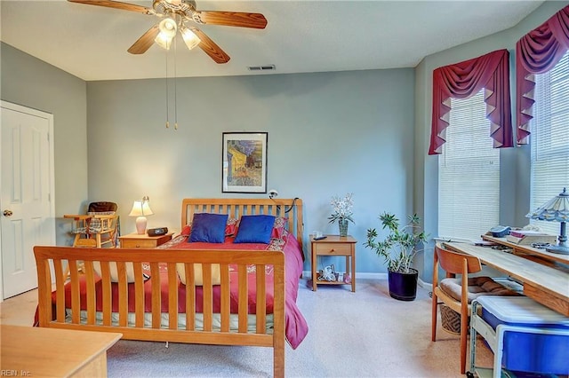 carpeted bedroom featuring a ceiling fan, visible vents, and baseboards