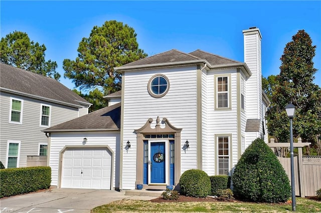 traditional home featuring a garage, a shingled roof, fence, concrete driveway, and a chimney